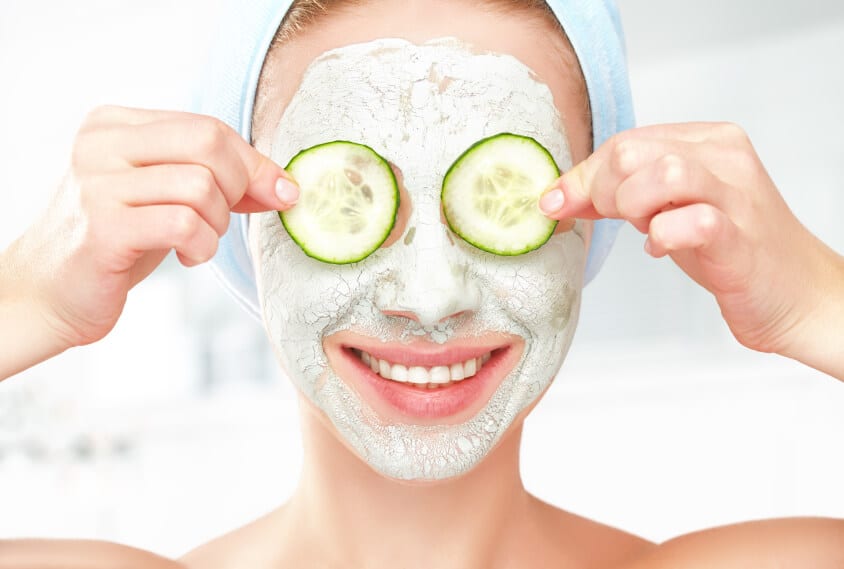 Woman putting cucumber in her eyes