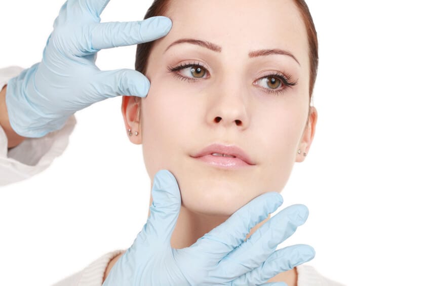 Doctor's hand inspecting a female patient's face