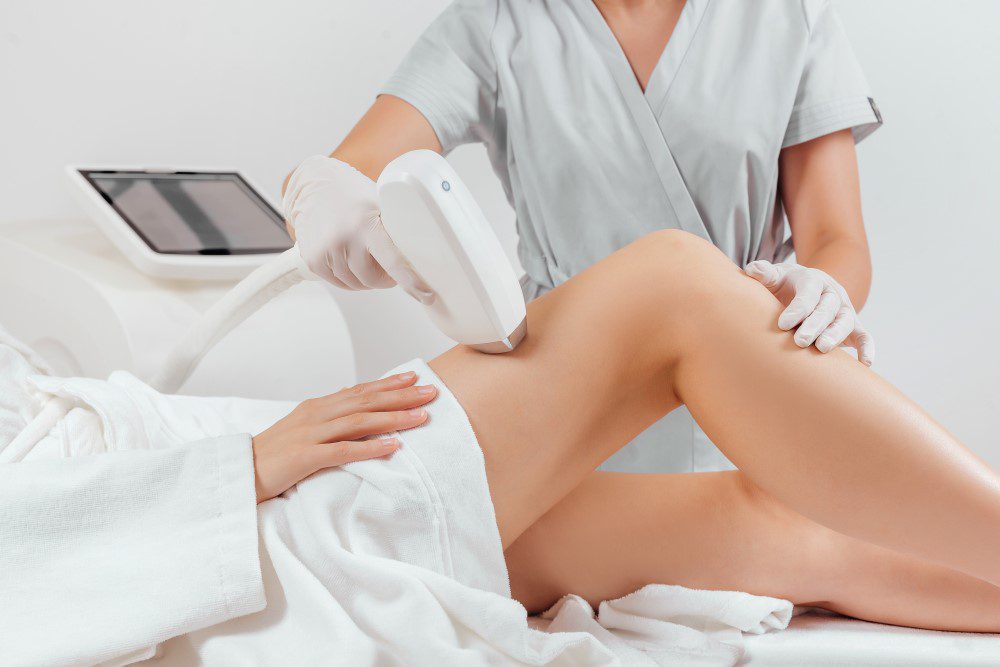 Young woman making body hair removal laser depilation in beauty center.