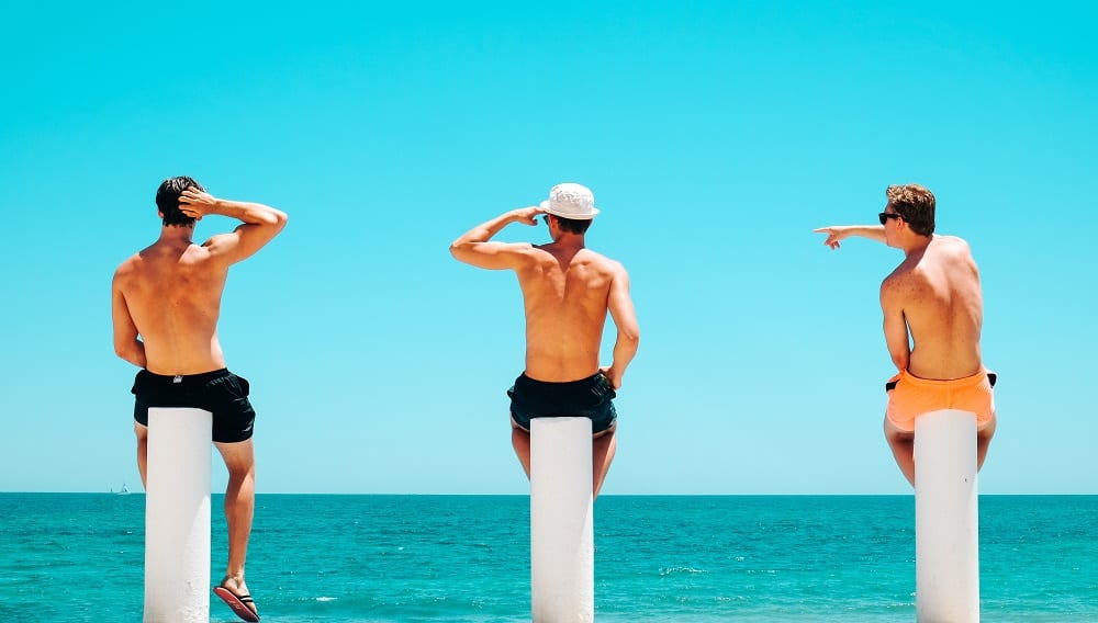 Three male friends sitting on beachside